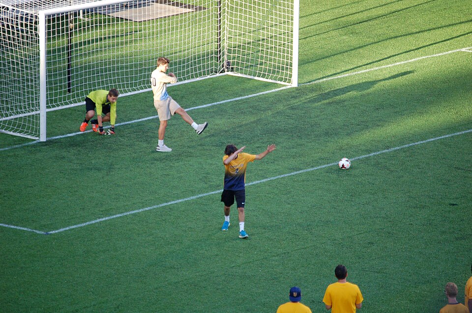 Vista aérea de un partido de fútbol en estadio lleno durante la noche