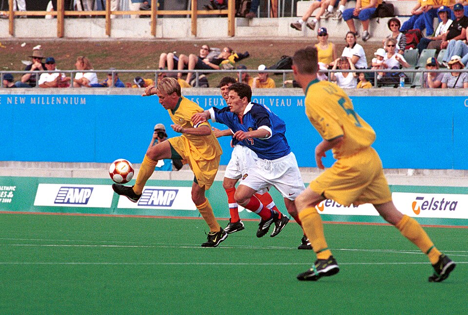 Hinchas viendo un partido internacional en un bar deportivo con camisetas y banderas